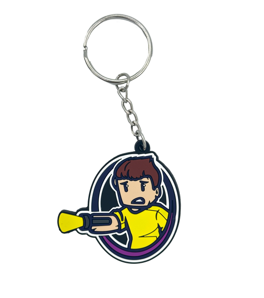 Schlüsselanhänger mit Tjulfar-Logo – Comicfigur im gelben Shirt mit Laserarm, violettem Kreisrahmen und Schlüsselring mit Kette. Gefertigt aus flexiblem Gummi, ideal für Schlüsselbund, Tasche oder als Fanartikel.